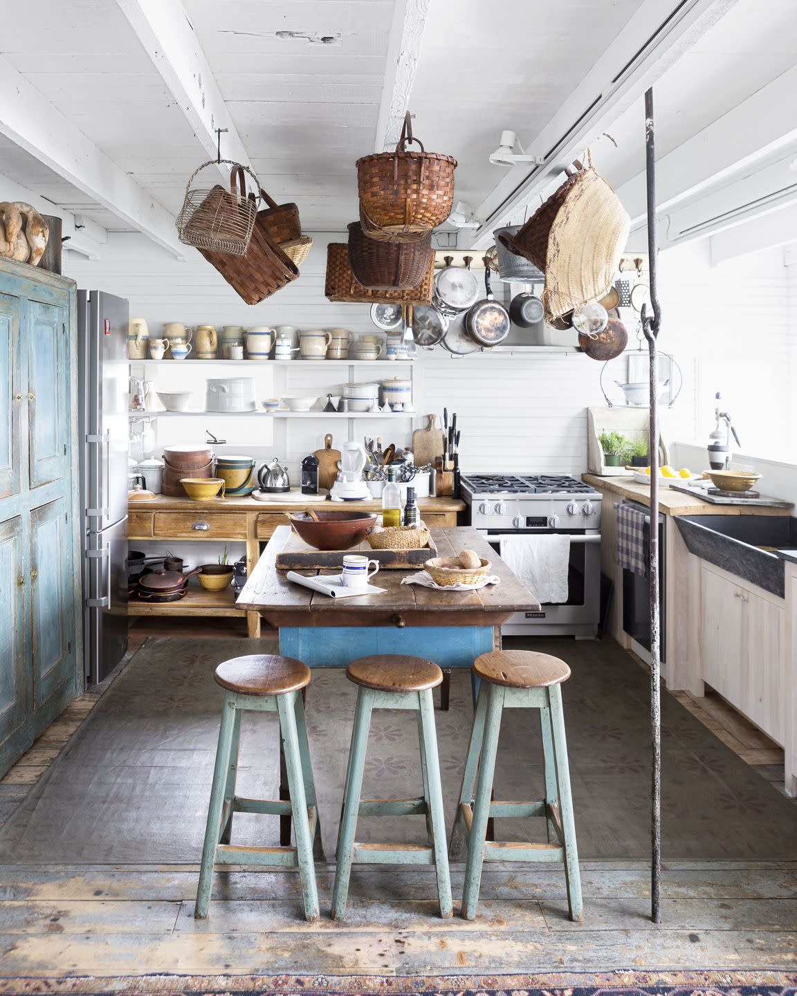 in a farmhouse kitchen baskets and cooking pots hang from the ceiling for a creative storage solution