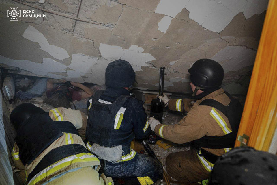 In this photo provided by the Ukrainian Emergency Service on Wednesday, March 13, 2024, emergency services work to save injured people trapped under an apartment building destroyed by a Russian attack in Sumy, Ukraine. (Ukrainian Emergency Service via AP)