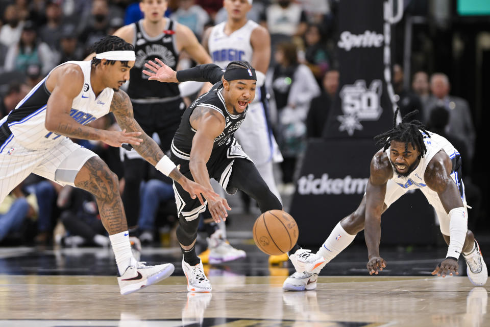 San Antonio Spurs' Devonte' Graham, center, fights for possession against Orlando Magic's Gary Harris, left, and Kevon Harris during the first half of an NBA basketball game, Tuesday, March 14, 2023, in San Antonio. (AP Photo/Darren Abate)