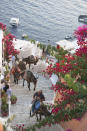 A man leads a pack of donkeys at dusk from the port up to the caldera-rim village of Oia on Santorini island, Greece, on June 29, 2021. The lifting of pandemic restrictions offers new opportunities to travel more mindfully to such bucket-list destinations, which used to be overrun by tourism. (AP Photo/Giovanna Dell’Orto)