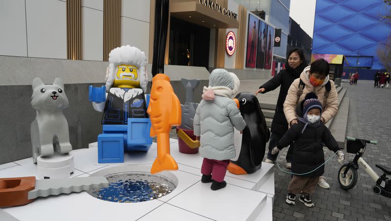 Children play near a display depicting an elderly person at a shopping mall in Beijing, Wednesday, Jan. 17, 2024. China’s population dropped by 2 million people in 2023 in the second straight annual drop as births fell and deaths jumped after the lifting of COVID-19 restrictions, the government said Wednesday.