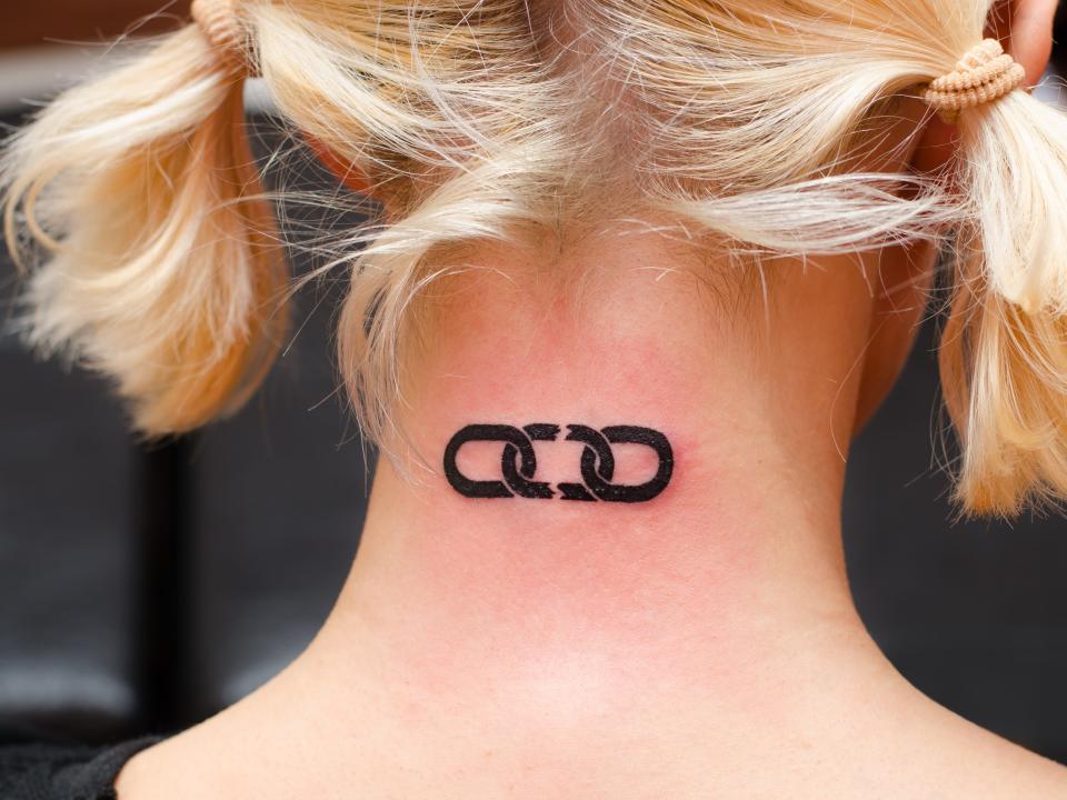 a broken chain tattoo on the back of a blonde person's neck