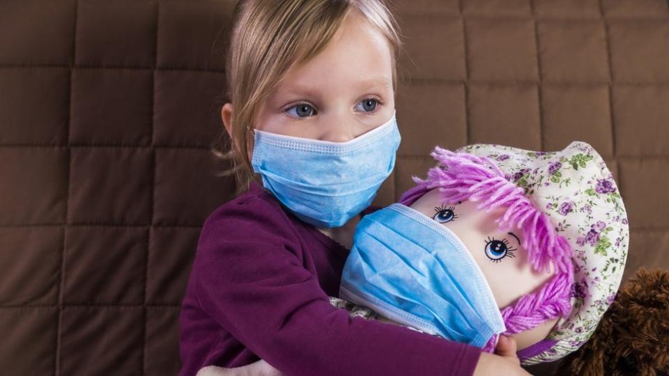 Niña con mascarilla y su muñeca.