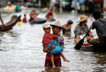 A woman carries her child as she walks through a flooded road in Kyaung Kone in Ayeyarwady division, Myanmar, August 12, 2016. REUTERS/Soe Zeya Tun