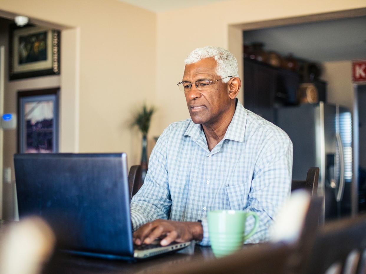 A senior black man works from his computer at home