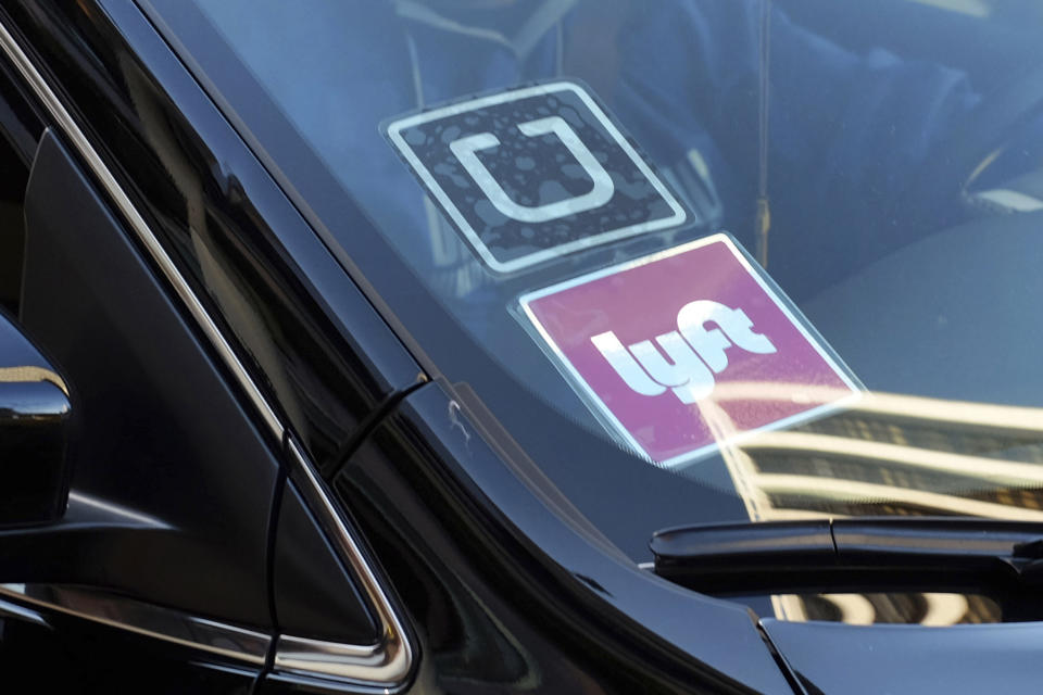 FILE - A ride share car displays Lyft and Uber stickers on its front windshield in downtown Los Angeles, Jan. 12, 2016. The California Supreme Court ruled Thursday, July 25, 2024, that app-based ride sharing and delivery services like Uber and Lyft can continue treating their drivers as independent contractors rather than employees.(AP Photo/Richard Vogel, File)