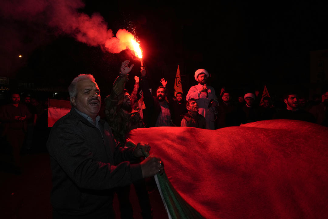 An Iranian demonstrator ignites a flare as others carry a Palestinian flag during an anti-Israeli gathering at the Felestin (Palestine) Sq. in Tehran, Iran, early Sunday, April 14, 2024. Iran launched its first direct military attack against Israel Saturday. The Israeli military says Iran fired more than 100 bomb-carrying drones toward Israel. Hours later, Iran announced it had also launched much more destructive ballistic missiles. (AP Photo/Vahid Salemi)