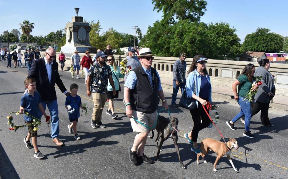 Attendees of a Memorial Day commemoration, including Stanislaus County Supervisor Terry Withrow, at left with his grandsons, carry flowers to toss into the Tuolumne River from the Seventh Street bridge Monday morning, May 29, 2023. Deke Farrow/jfarrow@modbee.com