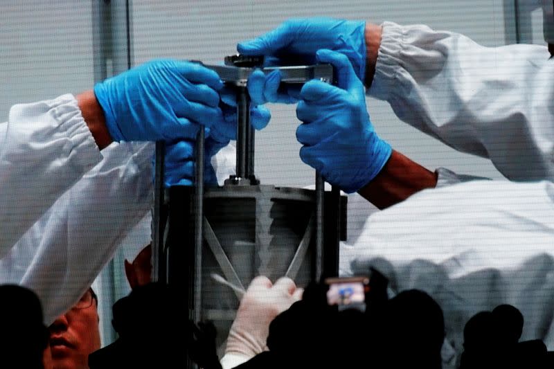 Screen shows footages of researchers holding an equipment carrying lunar sample from Chang'e-5 Mission, during an event on China’s lunar exploration program, at the National Astronomical Observatories of Chinese Academy of Sciences, in Beijing