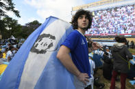 An Argentina soccer fan holds a Maradona flag while watching the national team lose to Saudi Arabia at a World Cup Group C soccer match, played on a large screen in the Palermo neighborhood of Buenos, Aires, Argentina, early Tuesday, Nov. 22, 2022. (AP Photo/Gustavo Garello)