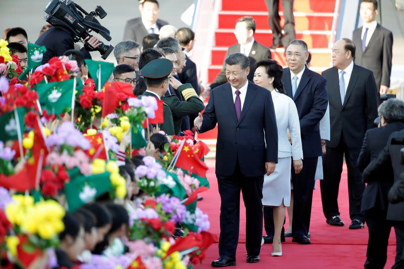 Chinese President Xi Jinping and his wife Peng Liyuan greet officials upon arriving at Macau International Airport in Macau