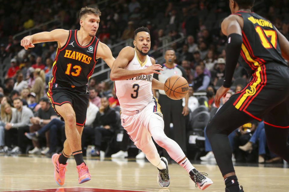 New Orleans Pelicans guard CJ McCollum (3) drives past Atlanta Hawks guard Bogdan Bogdanovic (13) and forward Onyeka Okongwu (17) in the first half of an NBA basketball game Sunday, March 20, 2022, in Atlanta, Ga. (AP Photo/Brett Davis)