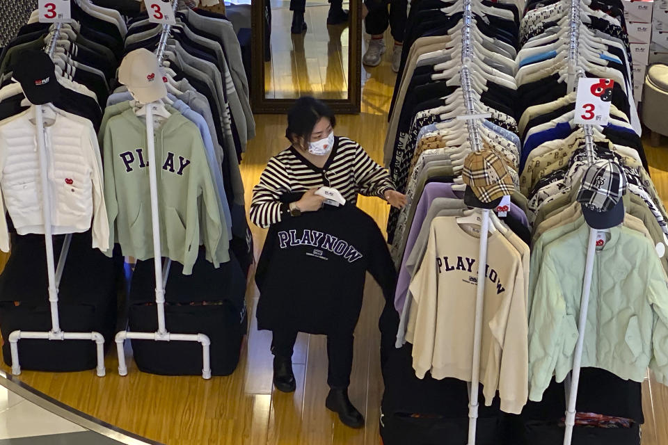 A worker wearing a face mask sorts through clothes on racks in a clothing store at a shopping mall in Beijing, Wednesday, Oct. 12, 2022. A meeting of the ruling Communist Party to install leaders gives President Xi Jinping, China's most influential figure in decades, a chance to stack the ranks with allies who share his vision of intensifying pervasive control over entrepreneurs and technology development. (AP Photo/Mark Schiefelbein)