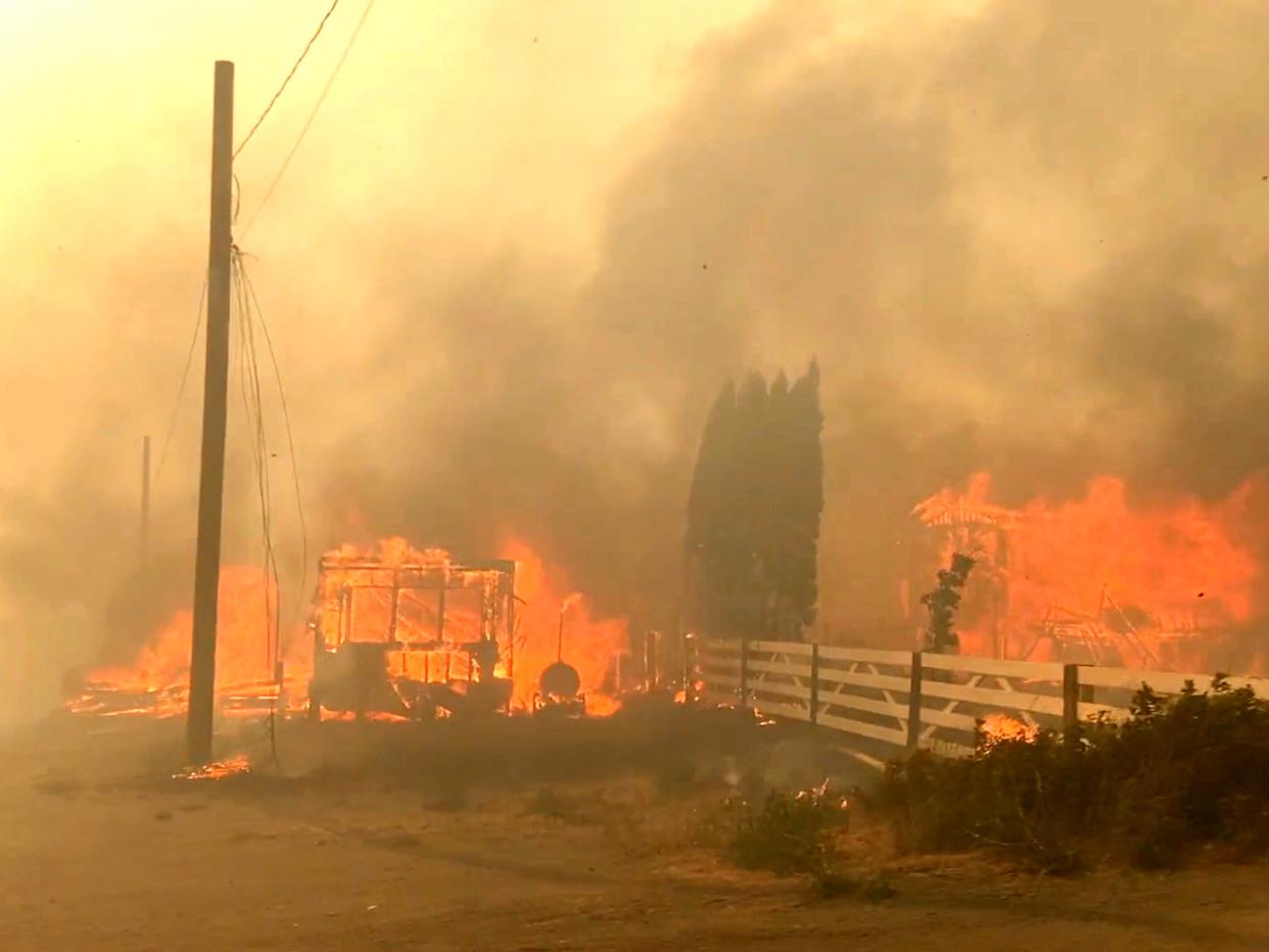 Flames rise from a burning building along a street during a wildfire in Lytton, British Columbia (2 Rivers Remix Society via Reuters)