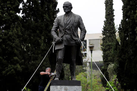 A statue of former U.S. president Harry Truman is tied with ropes as a supporter of the Greek Communist Party uses a grinder in a effort to bring the statue down during a demonstration against air strikes on Syria by the United States, Britain and France, in Athens, Greece April 16, 2018. REUTERS/Alkis Konstantinidis