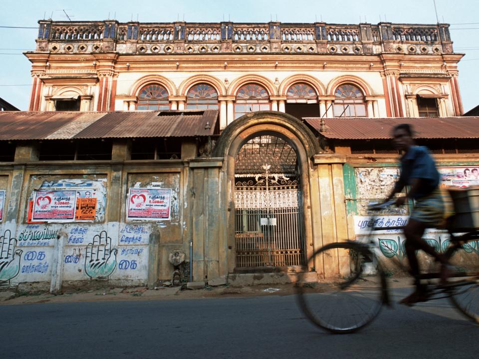 A man cycles past the shattered remains of an old mansion in Chettinad, Tamil Nadu, India, in 2005.