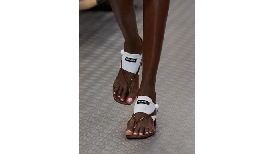 A close up of a model wearing Miu Miu shoes on the SS25 catwalk