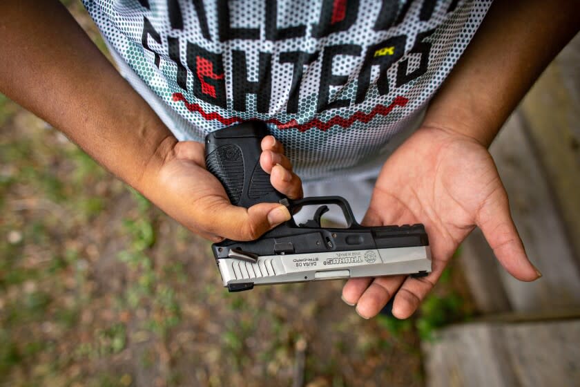 MINNEAPOLIS, MN - JULY 25: Romeal Taylor, a member of the Minnesota Freedom Fighters, sheds his riffle and tactical vest, only carrying a hand gun, at the meet-and-greet event to connect with the community on Saturday, July 25, 2020 in Minneapolis, MN. (Jason Armond / Los Angeles Times)