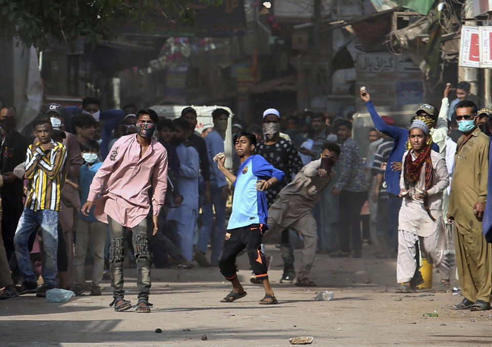 Supporters of Tehreek-e-Labiak Pakistan, a banned Islamist party, throw stones after police fire tear gas to disperse protests over the arrest of their party leader Saad Rizvi, in Karachi, Pakistan, Monday, April 19, 2021. The outlawed Islamist political group freed 11 policemen almost a day after taking them hostage in the eastern city of Lahore amid violent clashes with security forces, the country's interior minister said Monday. (AP Photo/Fareed Khan)