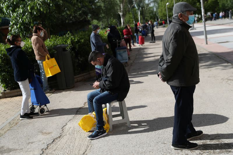 People queue to receive donated food from volunteers of Vecinos Parque Aluche association as the spread of the coronavirus disease (COVID-19) continues in Madrid