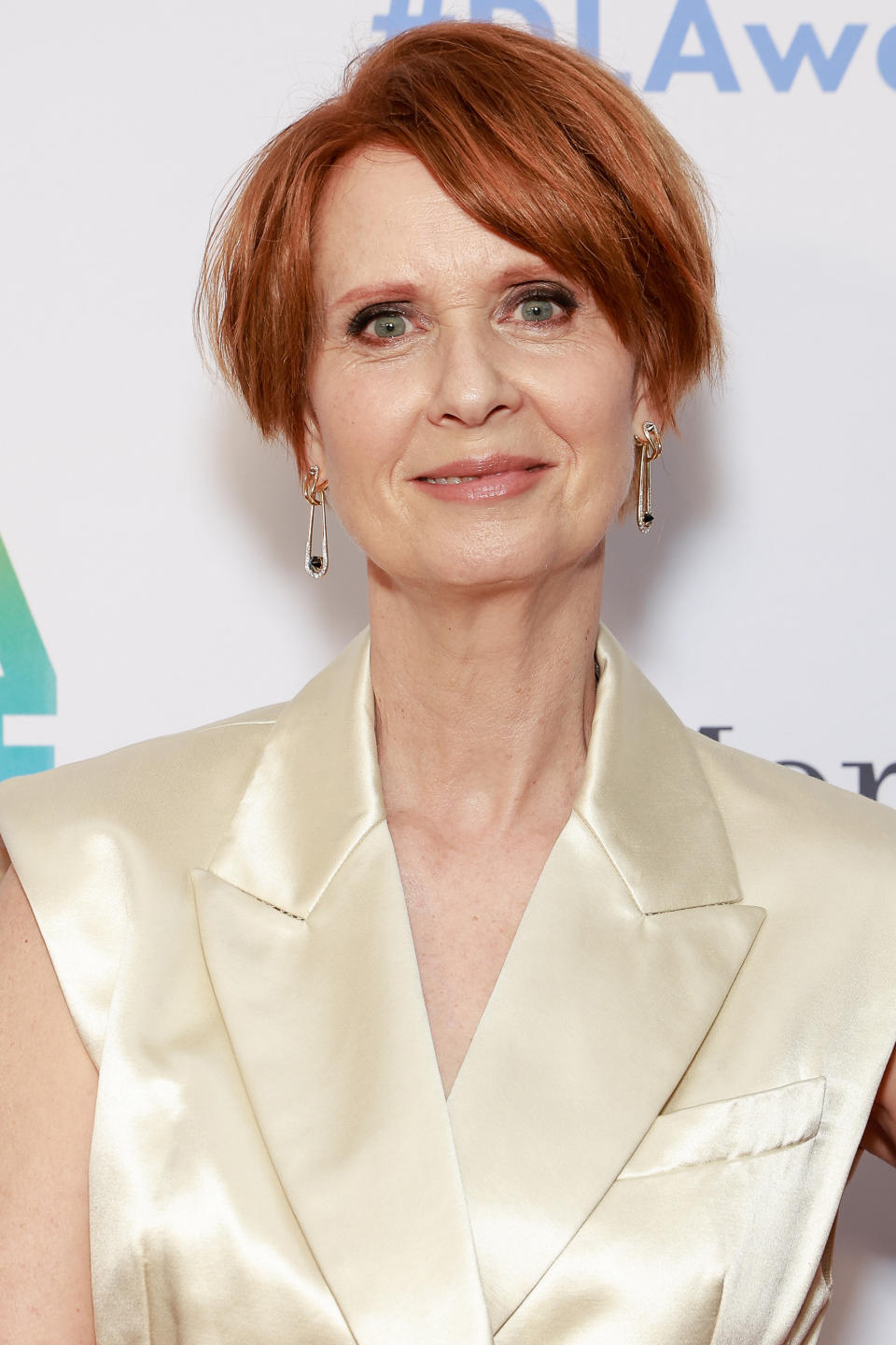 Cynthia Nixon, with short hair and wearing a sleeveless, satin-like vest