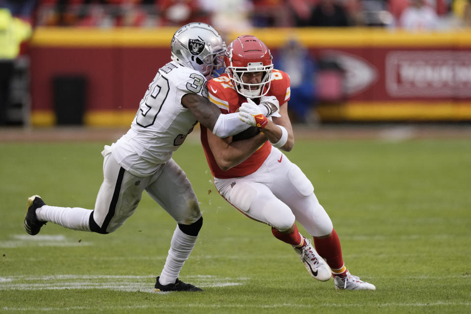 Kansas City Chiefs tight end Travis Kelce, right, is stopped by Las Vegas Raiders cornerback Nate Hobbs (39) during the first half of an NFL football game Monday, Dec. 25, 2023, in Kansas City, Mo. (AP Photo/Charlie Riedel)