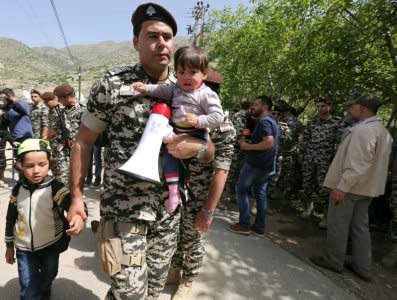 Lebanese general security member holds Syrian refugee children, who fled to Lebanon, as they wait for buses to go back to Syria from the southern village of Shebaa, Lebanon April 18, 2018. REUTERS/Aziz Taher