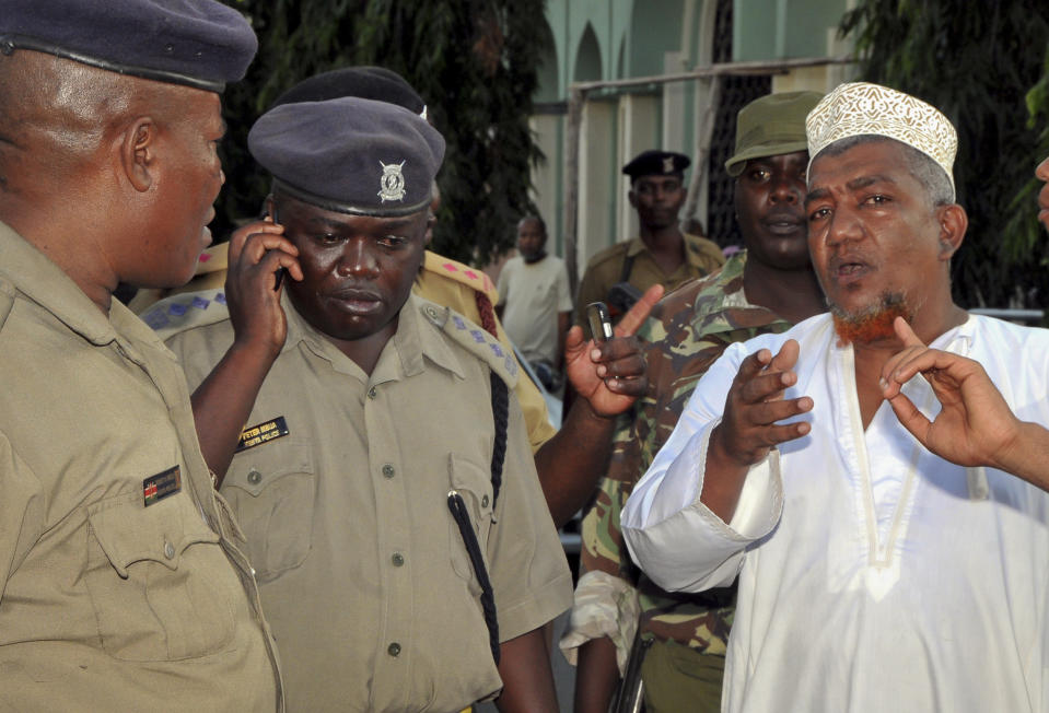 In this photo taken Wednesday, Feb. 5, 2014, muslim cleric Abubakar Shariff Ahmed, right, argues with senior police officers outside the Masjid Musa Mosque in Mombasa, Kenya. The lawyer for radical Islamic leader Abubakar Shariff Ahmed, who had been sanctioned by the United States and the United Nations for supporting the al-Qaida-linked Somali militant group al-Shabab, says his client has been assassinated Tuesday, April 1, 2014 along with another man whose identity has not yet been established, near the Shimo la Tewa prison in Mombasa, Kenya. (AP Photo)