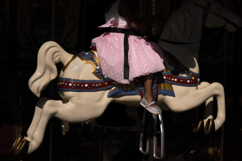 A young girl rides a horse on a carousel at Adventure City amusement park on the day of reopening in Anaheim, Calif., Friday, April 16, 2021. The family-run amusement park that had been shut since March last year because of the coronavirus pandemic reopened on April 16. (AP Photo/Jae C. Hong)