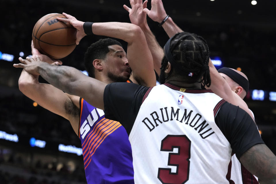 Phoenix Suns' Devin Booker looks to pass under pressure from Chicago Bulls' Alex Caruso and Andre Drummond during the first half of an NBA basketball game Friday, March 3, 2023, in Chicago. (AP Photo/Charles Rex Arbogast)