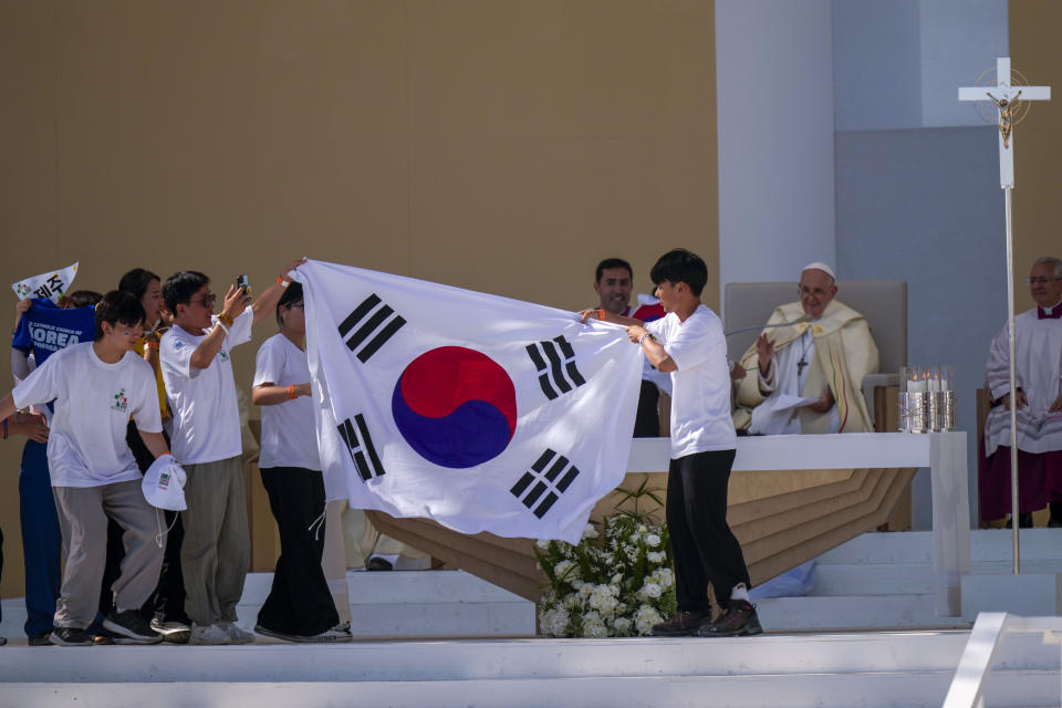 Jóvenes peregrinos de Corea del Sur festejan con su bandera nacional y el papa Francisco después de que él anunció que la próxima Jornada Mundial de la Juventud se llevará a cabo en Seúl en 2027, al concluir una misa en el parque Parque Tejo, el domingo 6 de agosto de 2023, en Lisboa. (AP Foto/Francisco Seco)