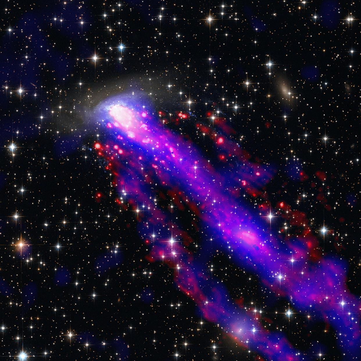 long thick blue-purple trails streak across space behind a galaxy