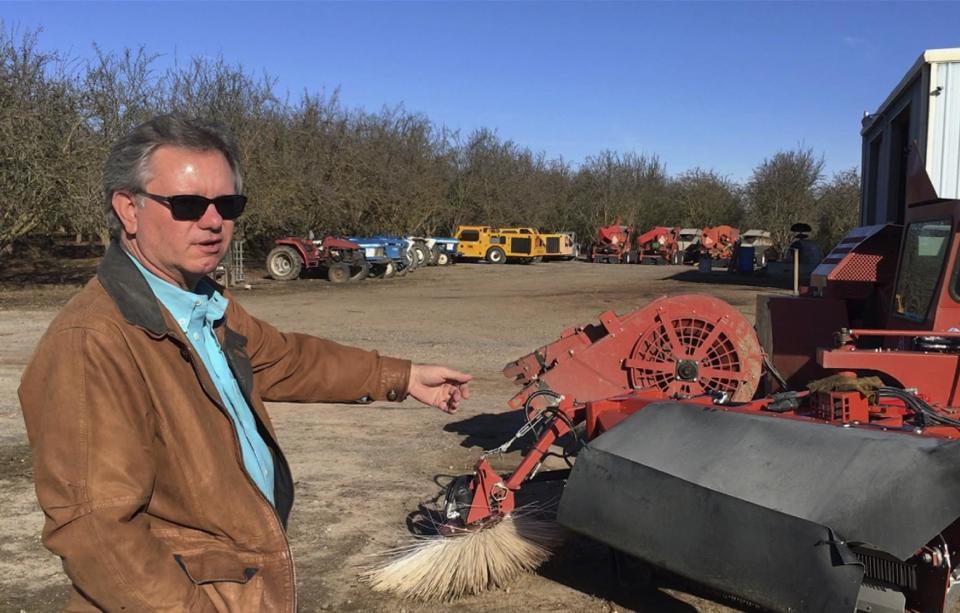 In this Dec. 27, 2016 photo, farmer Kevin Herman stands next to an almond sweeper at his ranch near Madera, Calif. Herman says that Donald Trump's campaign vow to deport millions of immigrants who are in the country illegally pushed him into buying more equipment, cutting the number of workers he'll need during the next harvest. (AP Photo/Scott Smith)