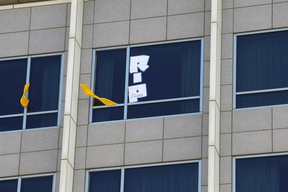 住在華航諾富特飯店檢疫的機師，在窗外掛上黃飄帶，還有機師特別用白紙條拼成「RIP」字樣，上面還寫著「CDC KILLS PILOTS」。（陳麒全攝）