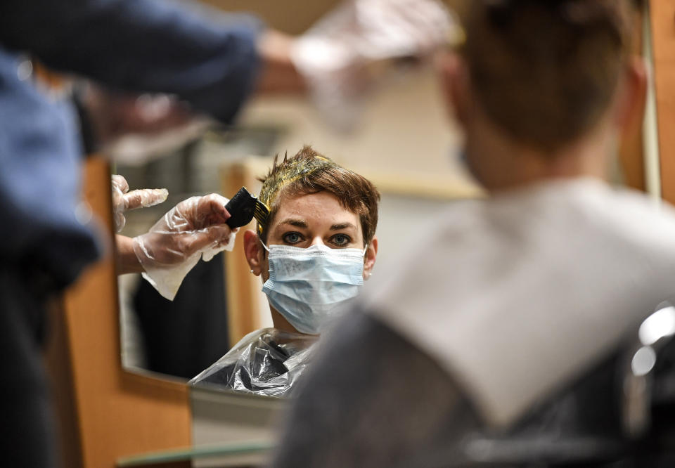 A customer gets her hair colored by a hairdresser at a barber shop in Gelsenkirchen, Germany, Monday, March 1, 2021. Hairdressers across Germany have reopened for business this morning after a more than 2-month closure, another cautious step as the country balances a desire to loosen restrictions with concern about the impact of more contagious coronavirus variants. (AP Photo/Martin Meissner)