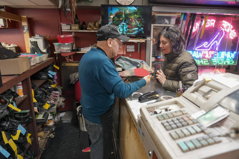 Jairo Cardenas, left, owner the Alpha Shoe Repair Corp., shows the repair made on a customer's shoes, Friday, Feb. 3, 2023, in New York. Business at the shop, which Cardenas has run for 33 years, is down 75% compared with prior to the pandemic. Shoe repairs typically bring in more money than shines. (AP Photo/Mary Altaffer)