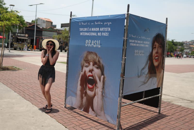 Una chica posa junto a una foto de la cantante Taylor Swift, antes de un concierto, tras la muerte de una aficionada debido al calor durante el concierto del primer día, en Río de Janeiro
