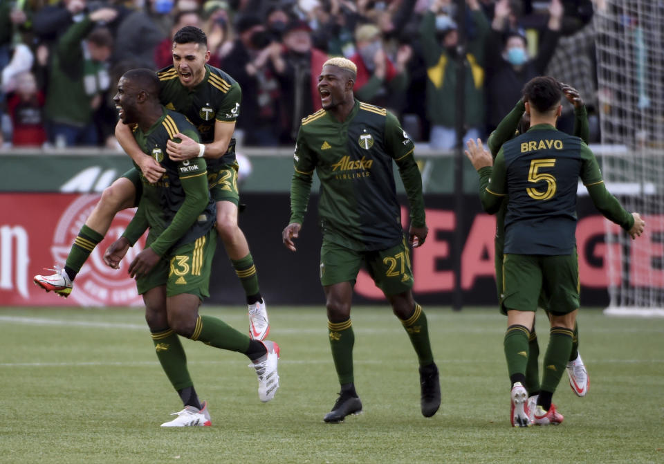 Portland Timbers defender Larrys Mabiala, left, is mobbed by teammates after scoring a goal during the first half of an MLS soccer match against the Minnesota United in Portland, Ore., Sunday, Nov. 21, 2021. (AP Photo/Steve Dykes)