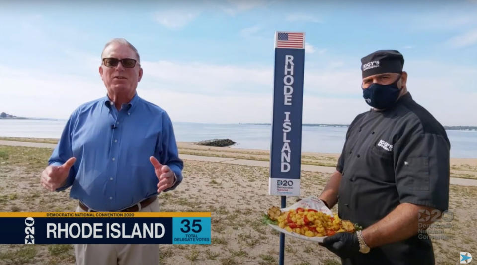 Rhode Island State Democratic Party Chairman Joseph McNamara is seen in a video frame grab casting the state's votes for the Democratic presidential nomination of former Vice President Joe Biden during the roll call vote of the virtual 2020 Democratic National Convention with John Bordieri, the chef of Iggy?s Boardwalk restaurant, holding a platter of fried calamari at his side on Oakland Beach in Warwick, Island, U.S., August 18, 2020. Picture taken August 18, 2020.   2020 Democratic National Convention/POOL via REUTERS