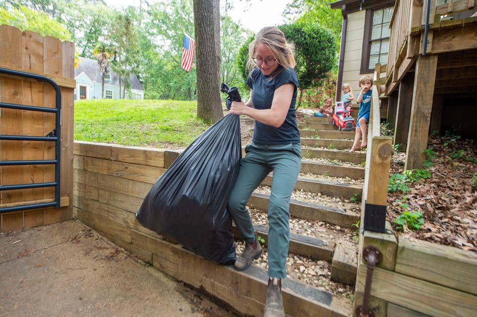 Jackson resident Mary Rooks, owner of Midstory Photography and a mother of four, carries some of the family's accumulated trash to the already building pile on the side of her house as seen in this file photo from Wednesday, April 12, 2023. The City is now facing a fine of $900,000 for failure to pick up residents' trash in April 2023.