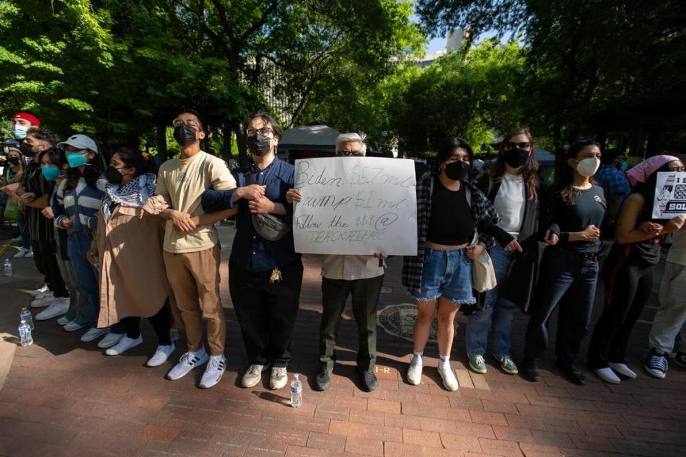 Pro-Palestinian activists lock arms on Tuesday, April 30, 2024, outside their tent encampment at Sacramento State as a counter-protester antagonized the group. The protesters are asking the university to divest from investments in Israel. José Luis Villegas/jvillegas@sacbee.com