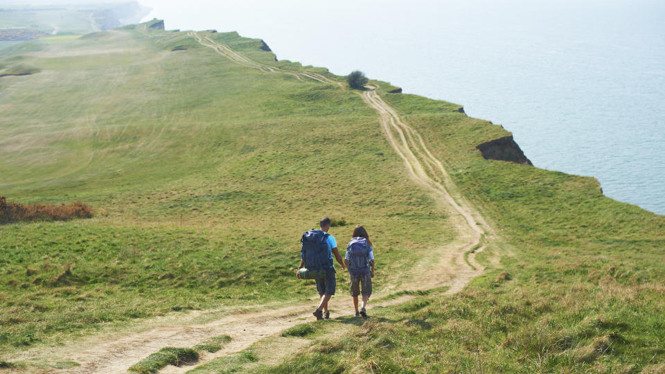 A couple hiking a grassy coastal path