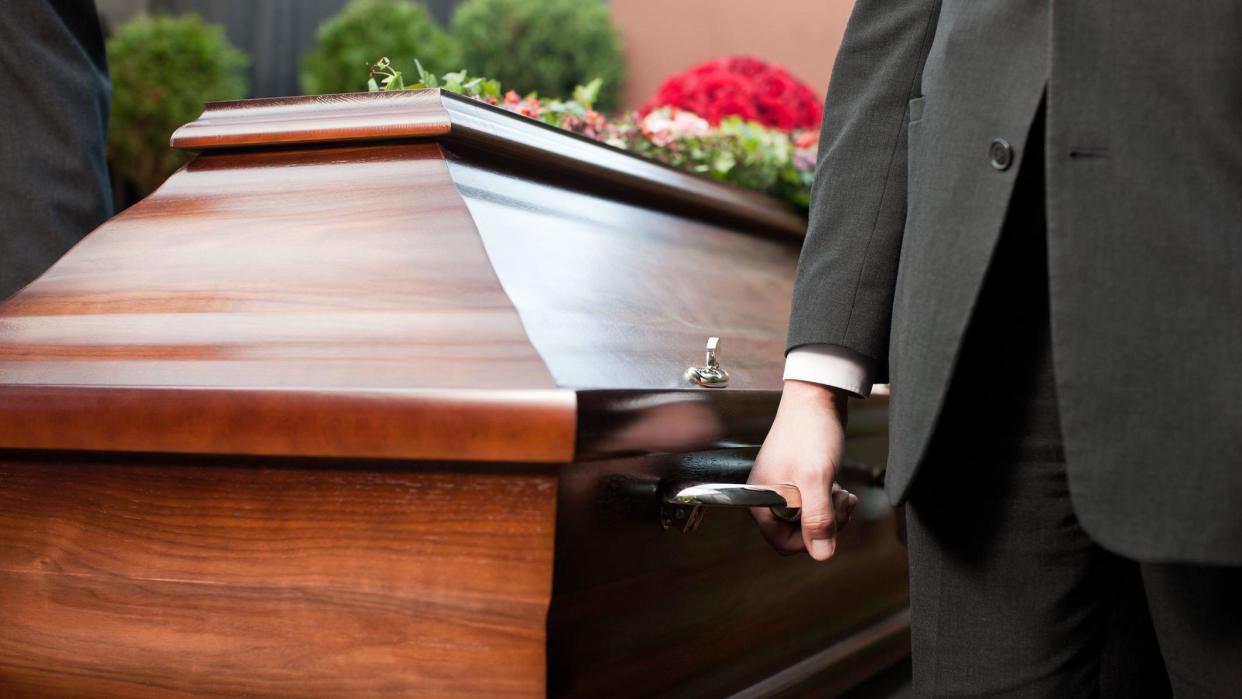 Close-up of coffin being carried by coffin-bearers