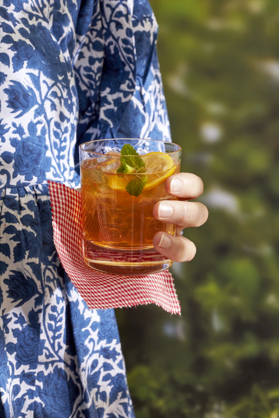 a person holding a glass of spicy ginger beer and bourbon cooler