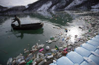 A fisherman paddles at the Potpecko accumulation lake covered with plastic bottles near Priboj, in southwest Serbia, Friday, Jan. 22, 2021. Serbia and other Balkan nations are virtually drowning in communal waste after decades of neglect and lack of efficient waste-management policies in the countries aspiring to join the European Union. (AP Photo/Darko Vojinovic)