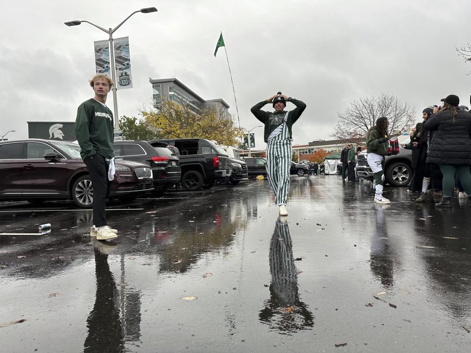 Michigan State University student Jack Bergman, right, waits for someone to throw a football to him in a tailgating area outside Spartan Stadium before the Michigan-Michigan State football game Saturday, Oct. 21, 2023, in East Lansing, Mich. Michigan State started selling alcoholic beverages at the stadium this fall. According to a survey by The Associated Press of Power Five conference schools and Notre Dame, 55 of 69 of them sell alcohol in the public areas of their stadiums on game days. (AP Photo/Mike Householder)