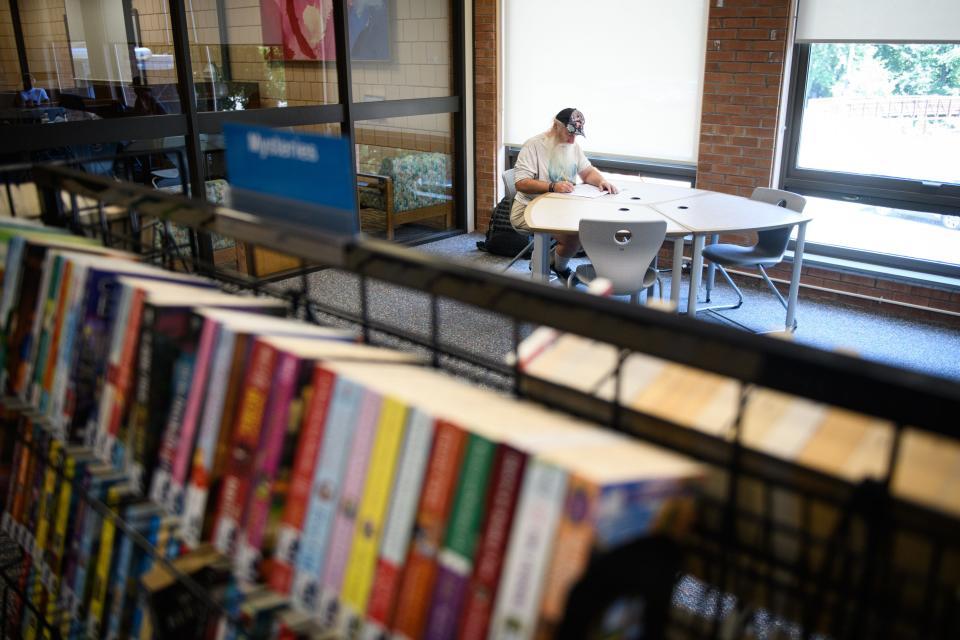 Curtis Stobie, who is homeless, writes down his thoughts while keeping cool in the Cumberland County Headquarters Library during a triple-digit heat index on Thursday, July 27, 2023.