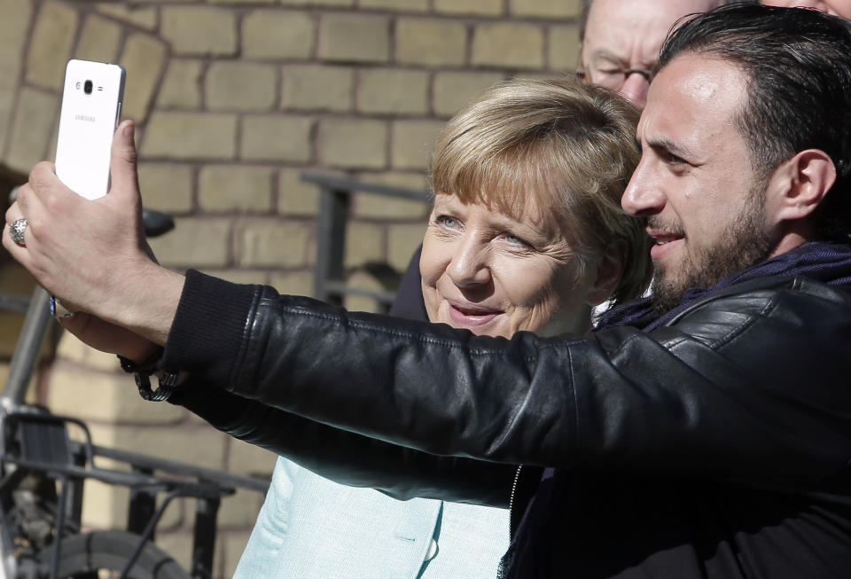 FILE - In this Sept. 10, 2015, file photo, refugee Rodin Saouan from Syria takes a picture of himself and German Chancellor Angela Merkel, left, during Merkel's visit at a registration center for migrants and refugees in Berlin, Germany. The U.N. refugee agency says it's giving its highest award to former German Chancellor Angela Merkel for her efforts to bring in more than 1 million refugees — mostly from Syria — into Germany, despite some pockets of criticism at both home and abroad. (AP Photo/Michael Sohn, File)