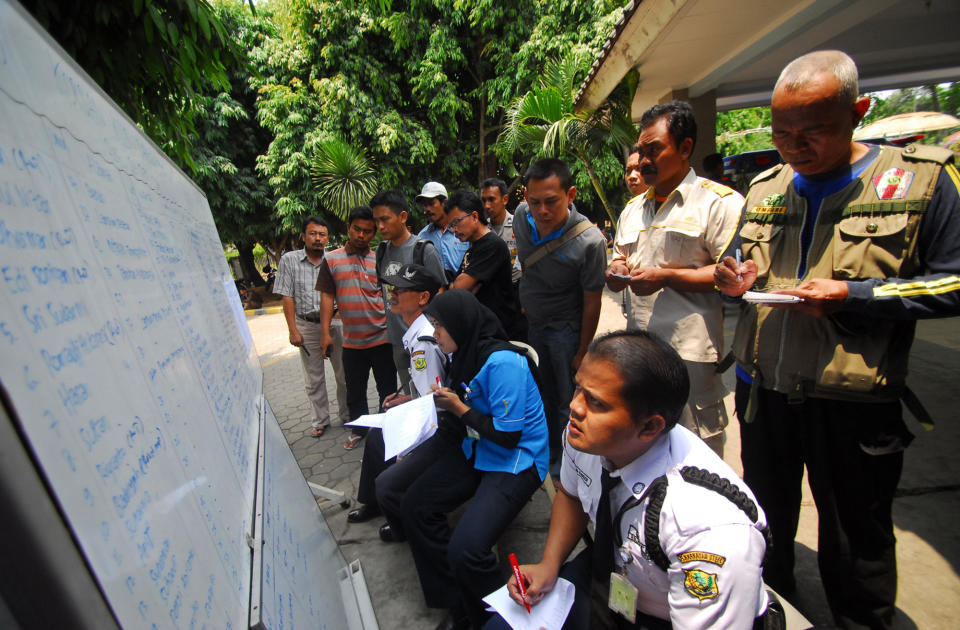 Relatives of the passengers of a ferry that sunk on Sunda straits check updates posted by authorities on a whiteboard at a hospital in Cilegon, Banten province, Indonesia, Wednesday, Sept. 26, 2012. A passenger ferry collided with a cargo ship and sank west of Indonesia's main island Wednesday morning, and at least eight people were killed, officials said. (AP Photo)