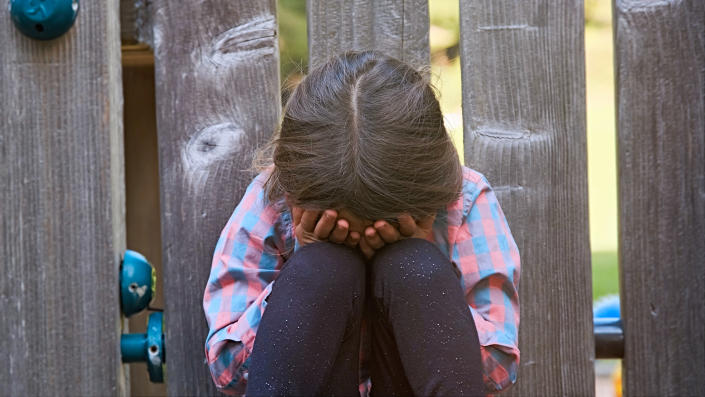 a young child crying with their hands to their face